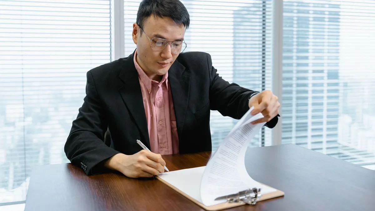 Cautious person reading a debt relief contract closely before signing at a kitchen table