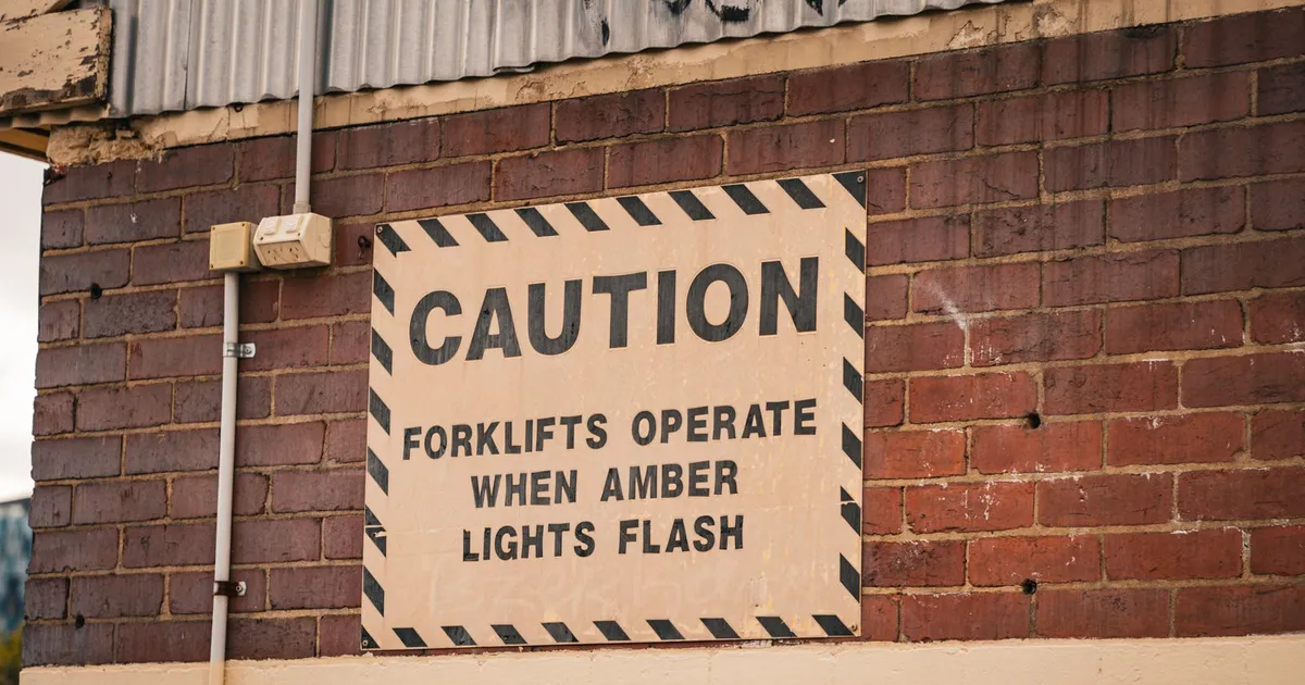 Yellow caution sign in front of a Canadian office building, a warning about debt relief scams
