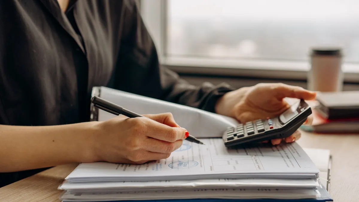Calculator and financial documents on a desk while a Canadian works out how much they could settle debt for