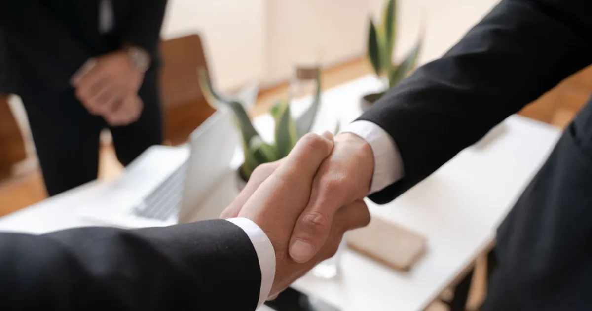 Handshake across a desk after a Canadian borrower agrees to settle debt for less than the full balance